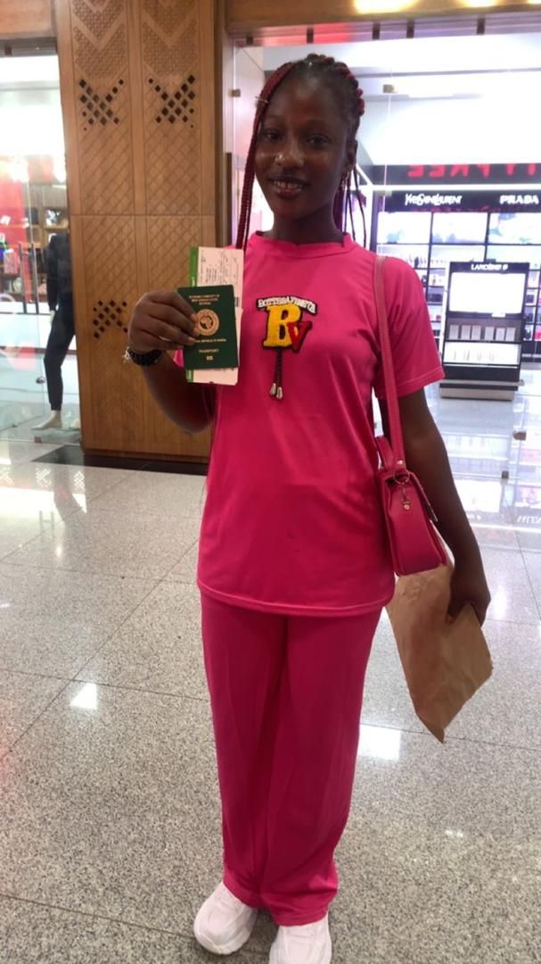 A young candidate holding her passport and boarding pass in an airport shopping concourse
