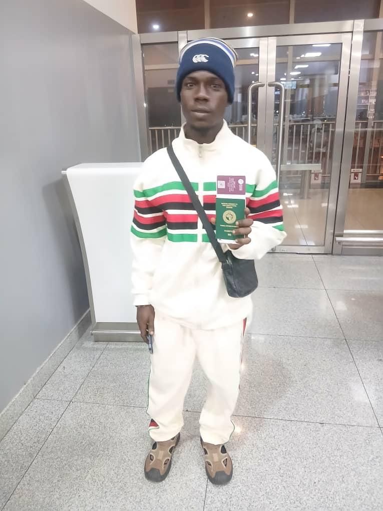 A candidate in a light shirt holding his travel documents near the terminal doors at night